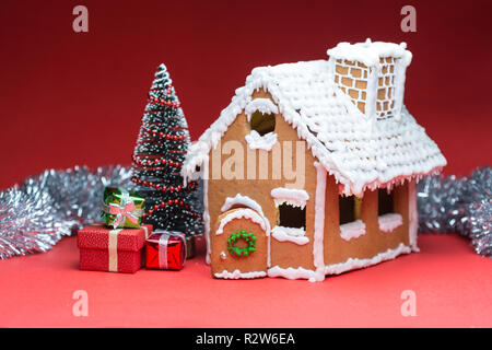 Maison avec des poupées et des biscuits de Noël sur fond rouge Banque D'Images