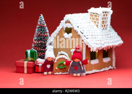 Maison avec des poupées et des biscuits de Noël sur fond rouge Banque D'Images