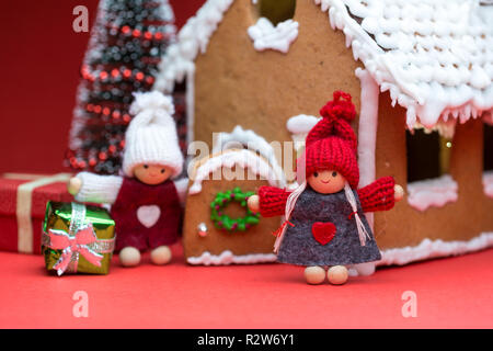 Maison avec des poupées et des biscuits de Noël sur fond rouge Banque D'Images