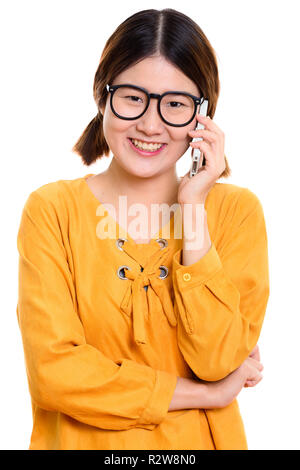 Studio shot of young happy Asian woman smiling while talking on Banque D'Images