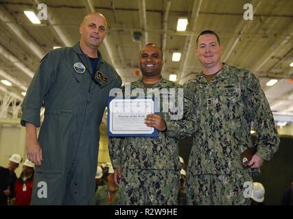 NEWPORT NEWS, Virginie (nov. 8, 2018), USS Gerald R. Ford (CVN 78) Commandant Capitaine John J. Cummings et Master Chief Operations Specialist Robert Laird Jr., posent pour une photo avec Ford's guerrier de la semaine, l'hôpital Corpsman 1re classe Amarpreet Gill, de New York, pendant un appel mains dans le hangar du navire. Ford est actuellement en post-shakedown la disponibilité de Huntington Ingalls Industries-Newport News Shipbuilding. Banque D'Images