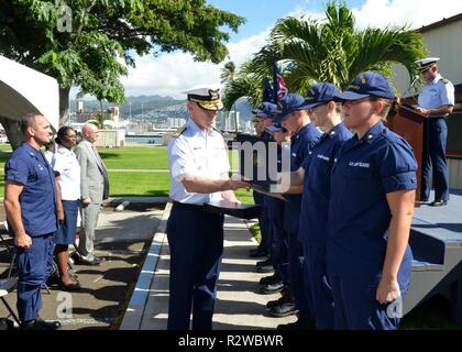 Adm arrière. Kevin Lunday, commandant de la Garde côtière canadienne, 14ème arrondissement, présente les membres de l'équipe avec leurs certificats méritoires mention élogieuse au cours d'une cérémonie à la base Honolulu, le 13 novembre 2018. La cérémonie a été la célébration de l'ouverture de la base de neuf Hale Kahu Moana clinique. Banque D'Images
