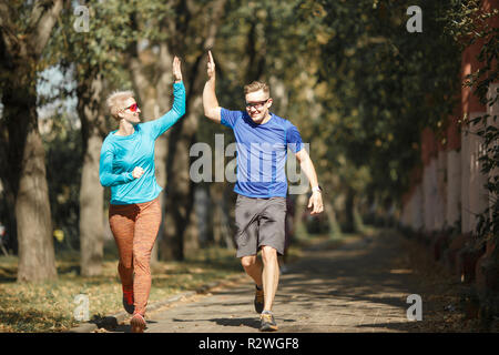 Image de l'homme et de la femme sportive faisant handshake on jogging du matin au parc. Arrière-plan flou. Banque D'Images