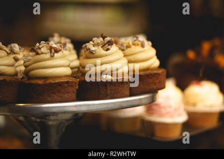 Cupcakes au caramel salé sur un plateau dans une boulangerie fenêtre avec un arrière-plan flou. Look vintage. Le format paysage. Banque D'Images