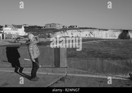 Femme regardant la mer de ses yeux de blindage les feux d'un soleil d'hiver à l'île de Wight Freshwater Bay Banque D'Images