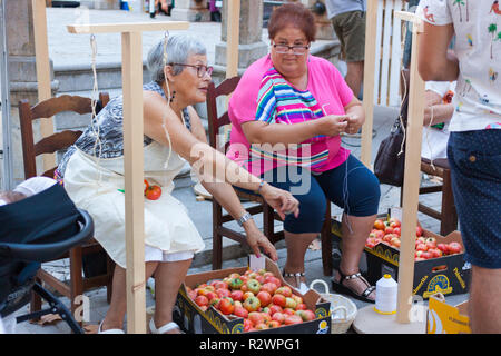 MARIA DE LA SALUT, Majorque, Espagne - 10 août 2018 : Les femmes des tomates lier ensemble pour former les grappes suspendues au cours de Tomate 'juste' Night Ramellet Banque D'Images