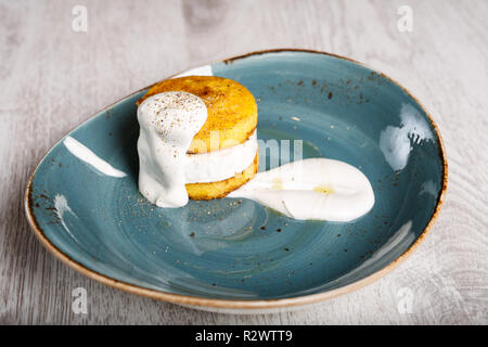 La polenta au fromage garni avec de la crème sur une plaque bleue Banque D'Images