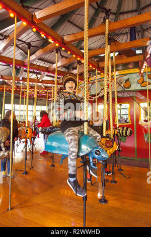 Neuf ans équitation le bug carousel au zoo du Bronx, New York, États-Unis d'Amérique. Banque D'Images