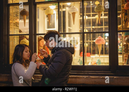 Londres, UK - Février, 2019. Un jeune couple de manger une glace à l'extérieur d'une boutique à Covent Garden. Banque D'Images
