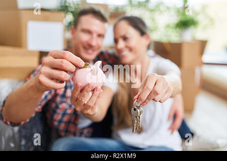 Couple heureux dans la nouvelle maison avec tirelire comme symbole pour financer Banque D'Images