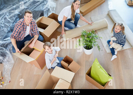 Famille et deux enfants se déplacent d'emballage boîtes dans leur nouvelle maison Banque D'Images