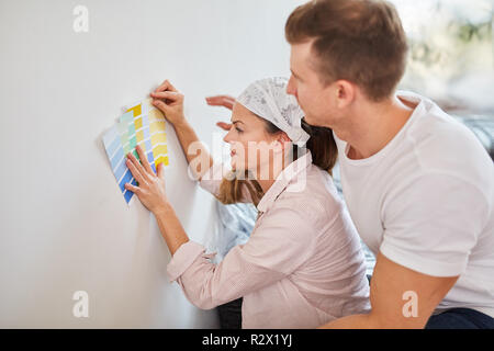 Jeune couple en papier peint peinture murale rend la décision pour in new house Banque D'Images