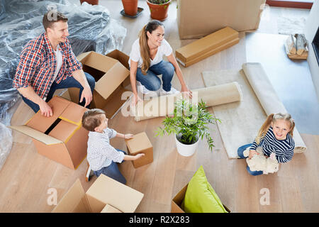 Les parents et deux enfants dans leur nouvelle maison des cartons d'emballage Banque D'Images