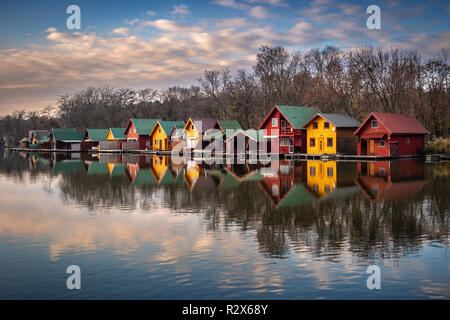 Tata, Hongrie - chalets de pêche par le lac (Derito Derito à) au coucher du soleil avec des réflexions et coloré Ciel et nuages Banque D'Images