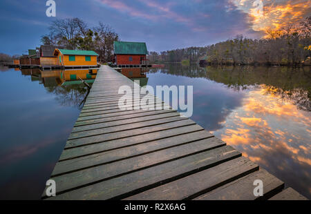 Tata, Hongrie - Pêche chalets sur petite île dans le lac (Darito Derito à) au coucher du soleil avec une ciel et nuages et pier Banque D'Images