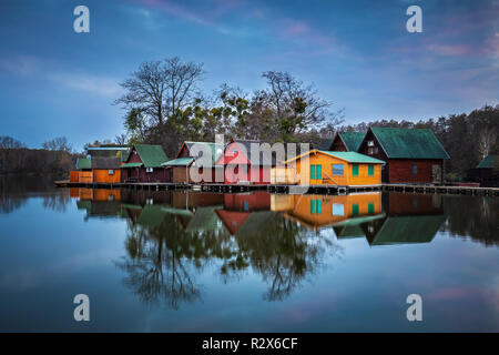 Tata, Hongrie - chalets de pêche en bois sur une petite île dans le lac (Derito Derito à) en novembre à l'heure bleue avec réflexion Banque D'Images