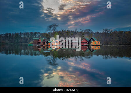 Tata, Hongrie - magnifique coucher de soleil sur les chalets de pêche en bois sur une petite île dans le lac (Derito Derito à) en novembre avec la réflexion Banque D'Images