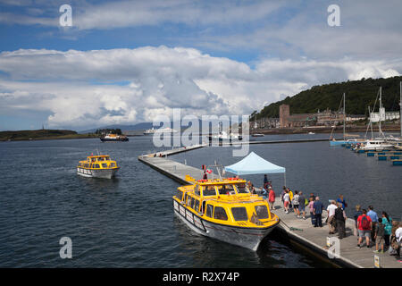 Ferries à les pontons dans la baie d'Oban, Argyll, Scotland en tenant pour passagers et d'un navire de croisière dans le port de plaisance. Banque D'Images
