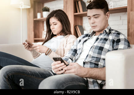 Concentrated brunette homme lecture d'e-mails en smartphone Banque D'Images