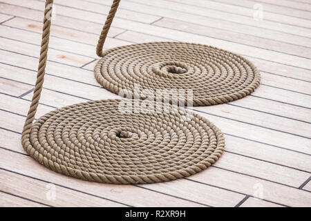 Vieux objets nautiques concept. Arrondi cercle commode ancienne bobine de corde sur plancher en bois. Banque D'Images