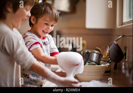 Deux frères jouant avec de l'eau savonneuse pendant le lavage. Banque D'Images