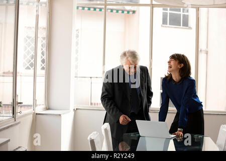 Smiling business colleagues discussing travailler sur un ordinateur portable. Banque D'Images