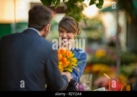 Young businessman présente son collègue avec un bouquet de tulipes dans un marché aux fleurs. Banque D'Images
