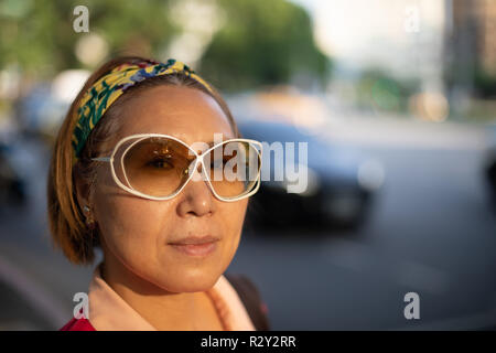 Portrait of smiling mature woman taïwanais d'origine chinoise au soleil du soir à l'encontre de big city traffic toile Banque D'Images