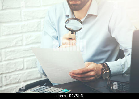 Businessman à travers une loupe aux documents Banque D'Images