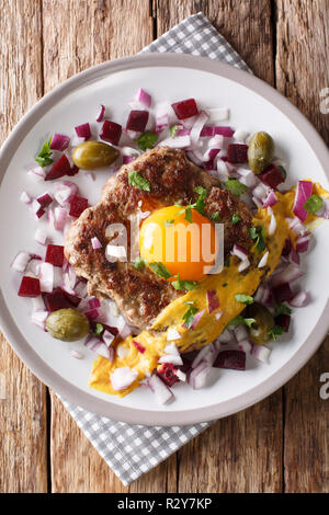 Une cuisine danoise : steak ou Pariserbof parisien avec des légumes et la moutarde gros plan sur une assiette sur la table. Haut Vertical Vue de dessus Banque D'Images