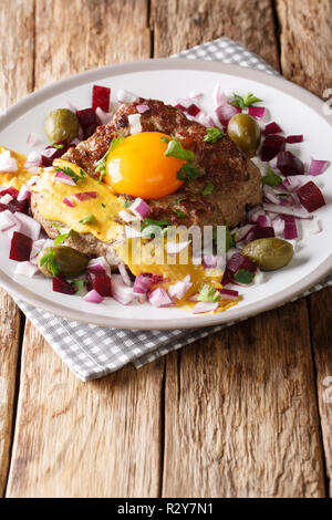 Tartare de boeuf frites ou Steak Parisien - Pariserbof avec des œufs, des légumes et de la moutarde gros plan sur une plaque verticale sur la table. Banque D'Images