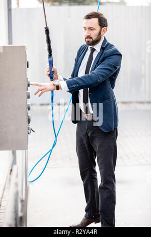 Businessman lave-voiture sur un self service lavage de voiture, debout avec des armes à feu près de l'automate de lavage Banque D'Images