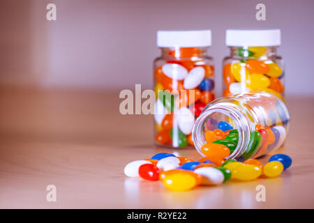 Pilules multicolores s'échappant d'une bouteille de pilules contre un arrière-plan flou Banque D'Images