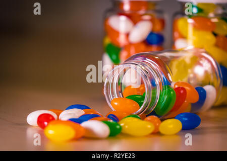 Pilules multicolores s'échappant d'une bouteille de pilules contre un arrière-plan flou Banque D'Images