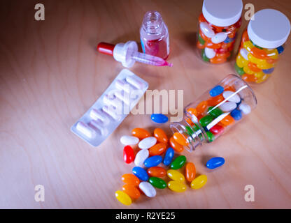 Pilules multicolores s'échappant d'une bouteille de pilules contre un arrière-plan flou Banque D'Images