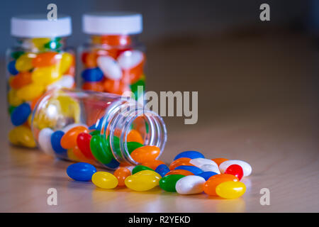 Pilules multicolores s'échappant d'une bouteille de pilules contre un arrière-plan flou Banque D'Images
