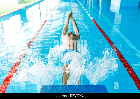 Photo de l'athlète dans le bouchon en caoutchouc bleu piscine sur le dos pendant l'entraînement en piscine Banque D'Images