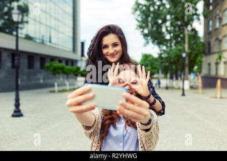 Jolies filles mignonnes selfies making funny dans la rue, de s'amuser ensemble, de joie, de bonheur, d'amour, d'amitié, de soeurs. Banque D'Images