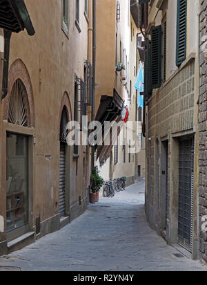 Vue sur les vélos garés dans une rue étroite pavée typique entre les immeubles de grande hauteur dans le centre de Florence, Toscane, Italie Banque D'Images