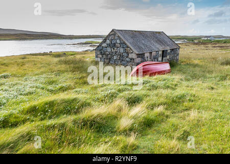 Chalet traditionnel en pierre rouge et bateau à rames par la côte, Uist, îles Hébrides, Ecosse, Royaume-Uni, Europe Banque D'Images