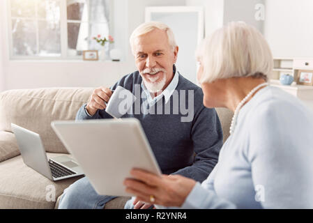 Belle femme aux cheveux gris montrant des images sur la tablette Banque D'Images