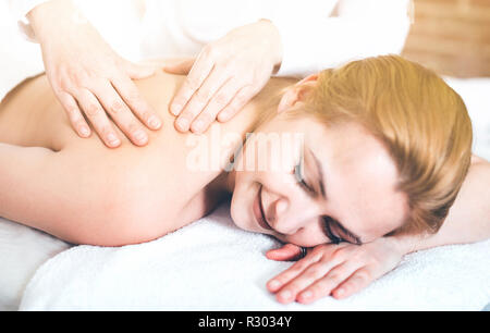 Masseuse positive joyeux rend le massage relaxant à la zone d'épaule jeune femme dans un salon de beauté Banque D'Images