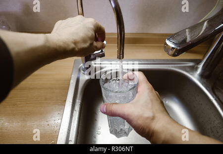 Un homme se verse un verre d'eau du robinet. Première personne vue grand angle Banque D'Images