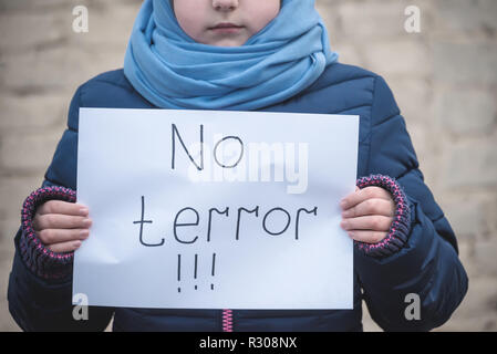 Fille de réfugiés avec une inscription sur une feuille blanche 'pas de terrorisme" Banque D'Images