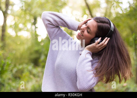 Les jeunes Européens de race blanche femme ou fille d'écouter de la musique avec des casques de manière énergique et dansant déménagement ses cheveux avec de l'énergie dans la nature ou très heureux f Banque D'Images