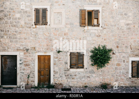 La façade d'un vieux bâtiment ordinaire avec une porte et des fenêtres au Monténégro. L'habitat traditionnel. Banque D'Images