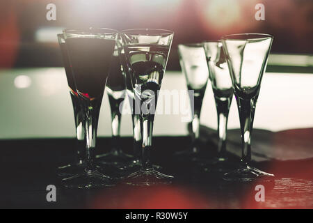 Verres dans le night club, rempli de boissons alcoolisées sombre et clair avec lumières colorées en arrière-plan Banque D'Images
