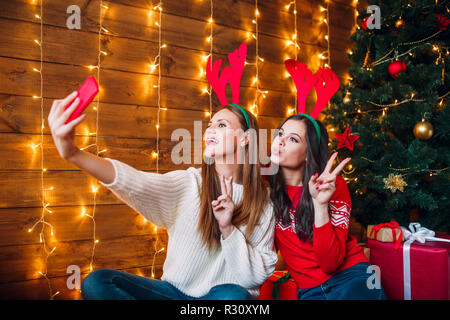 Copines prenant un sourire avec selfies. smartphone Ambiance de Noël. Banque D'Images