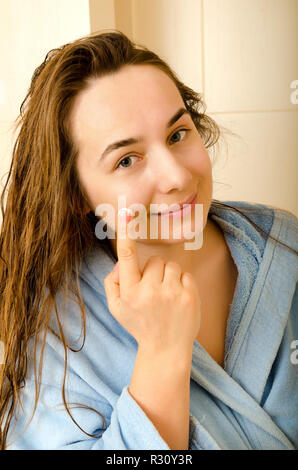 Femme avec la crème dans une salle de bains Banque D'Images