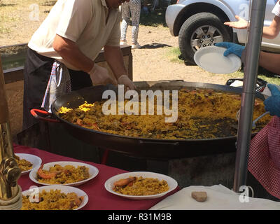 Un homme cuisiniers et sert la Paella espagnole à l'extérieur dans un grand plat. Repas populaire. La cuisine espagnole et de la culture. Valence Banque D'Images